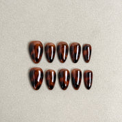Glossy press-on nails in deep tortoiseshell brown with subtle gradient shine