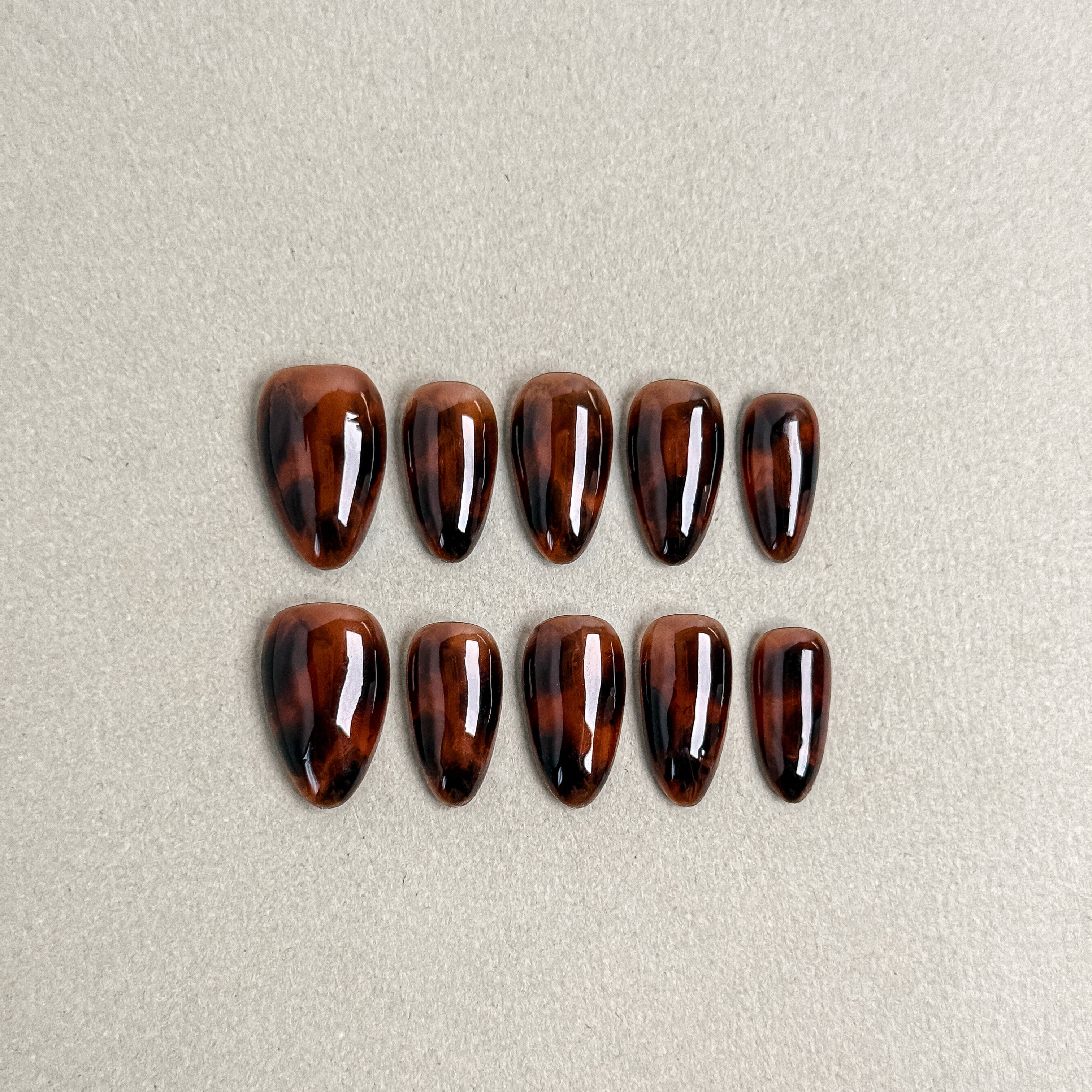 Glossy press-on nails in deep tortoiseshell brown with subtle gradient shine