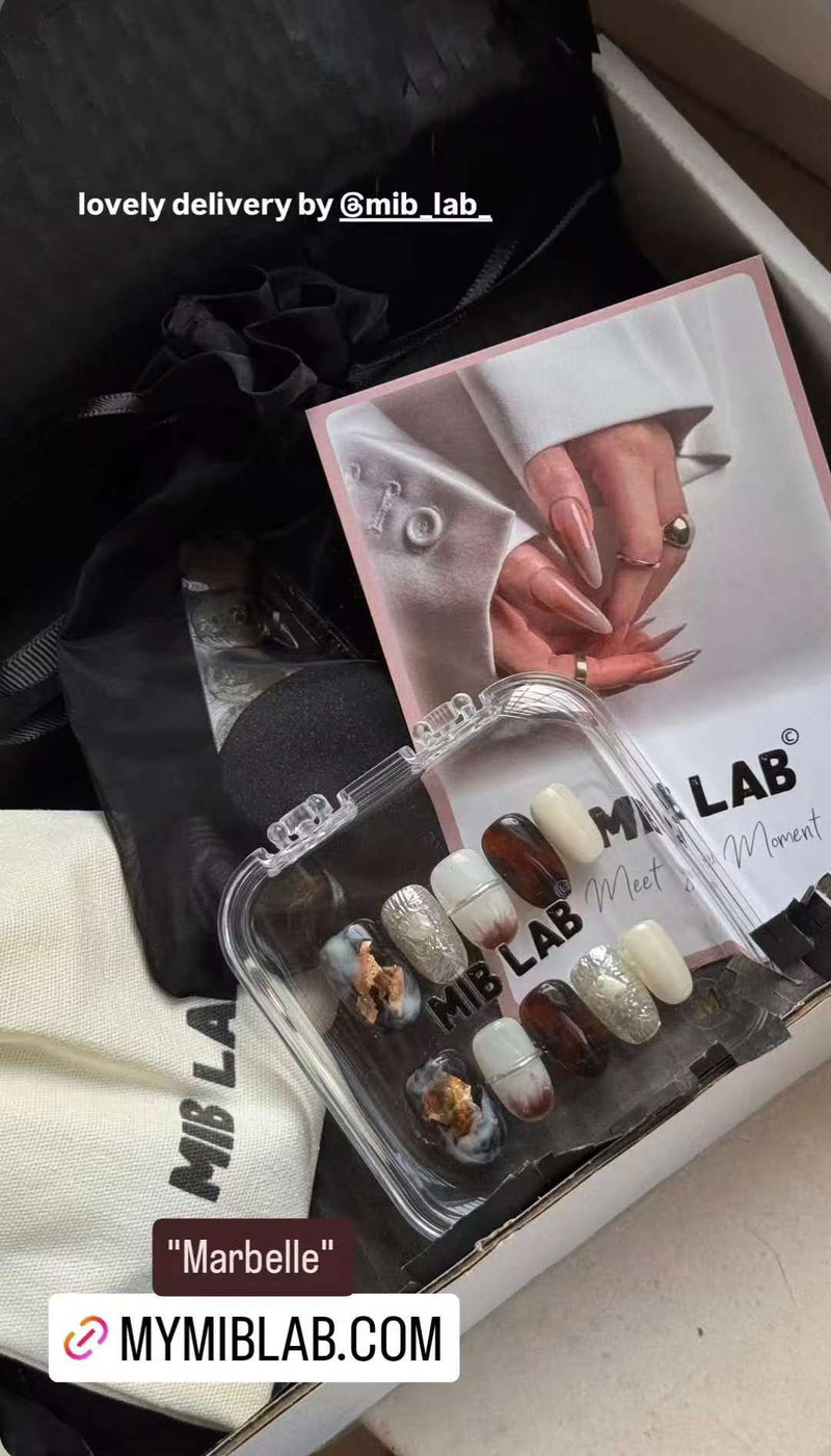 Mise en scène du set MIB LAB “Marbelle” : faux ongles effet marbre avec touches dorées dans une boîte transparente, avec MYMIBLAB.COM.