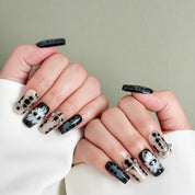 Model wearing MIBLAB Bones black and silver Halloween-themed press-on nails, handcrafted reusable design available in Geneva.