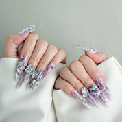 Model wearing At Last nails featuring 3D gem accents and shimmering purple details