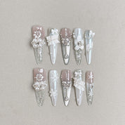 Long stiletto press-on nails with silver chrome tips and 3D white floral decorations for an elegant bridal style
