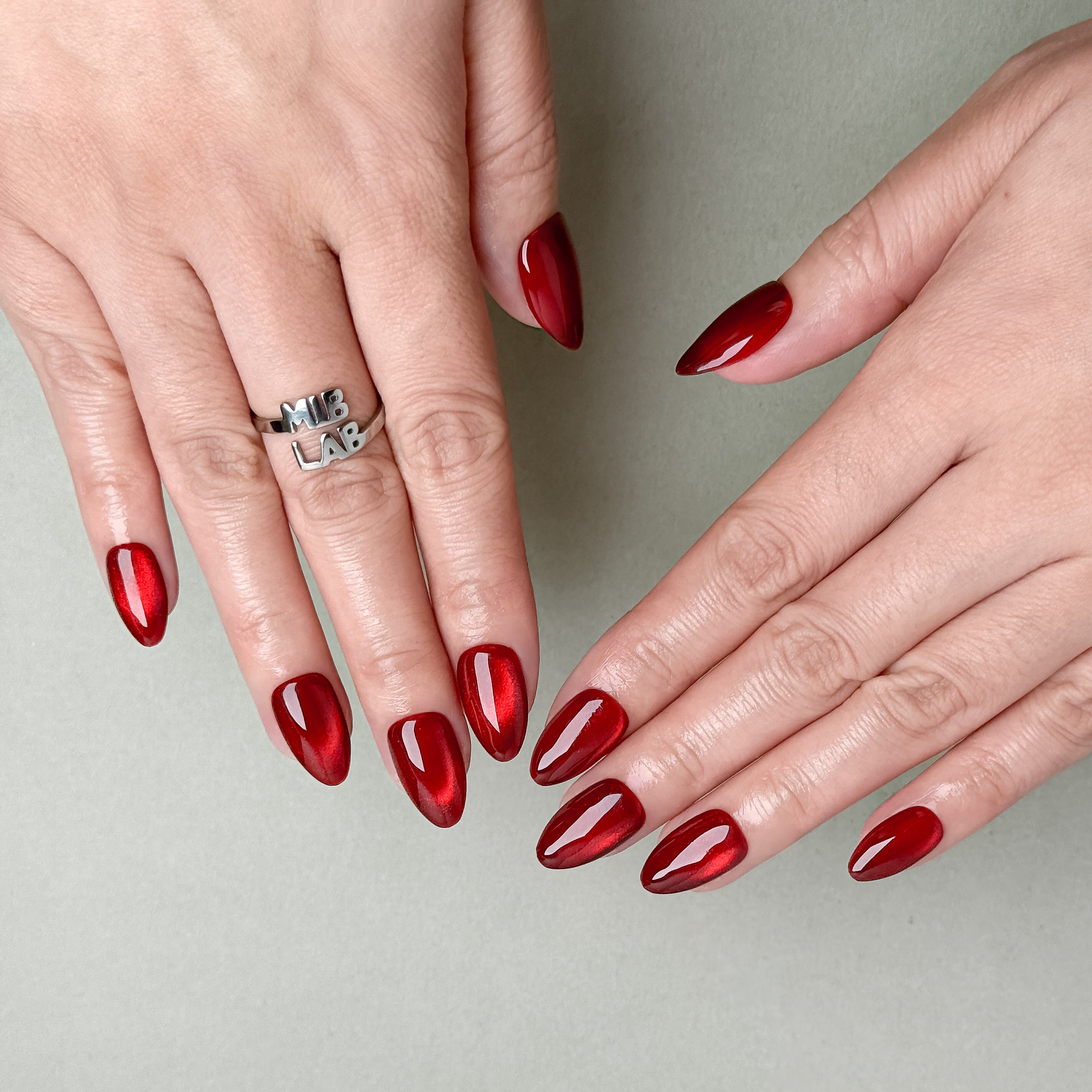 Hands featuring MIBLAB Merry Me press-on nails in shiny cherry red finish, luxury reusable manicure from Geneva boutique.