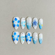White and blue press-on nails with bold floral patterns and glossy finish