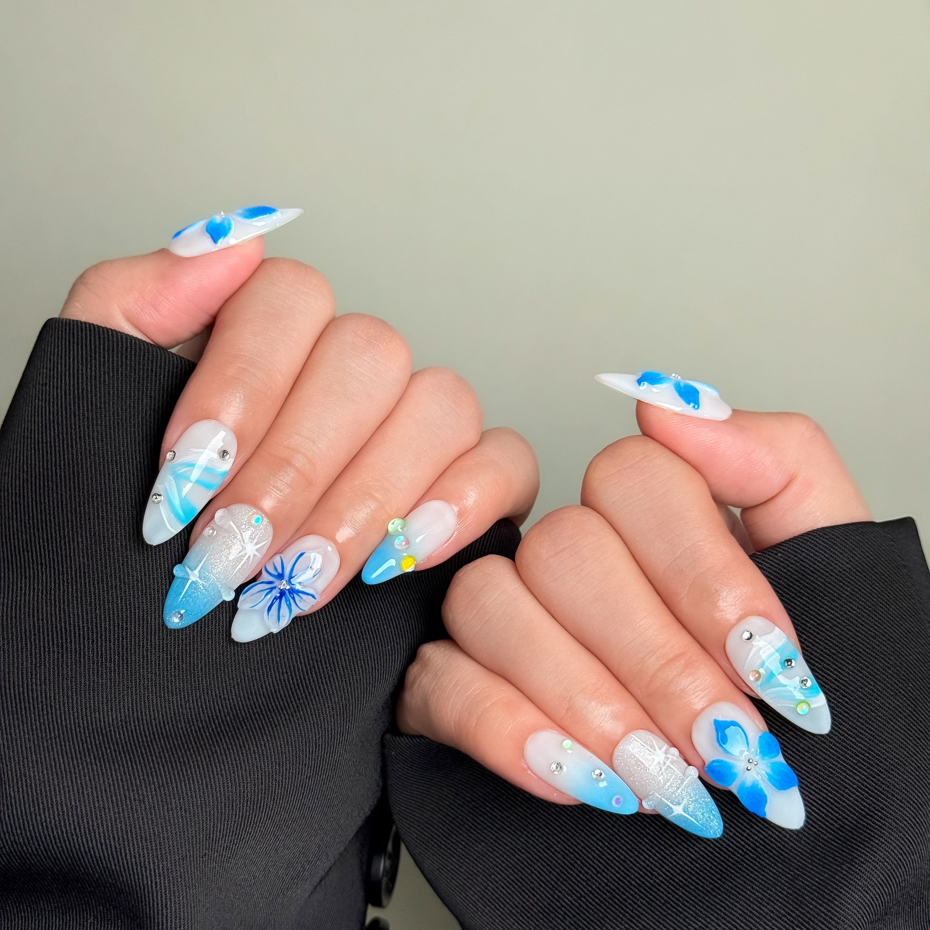 Model wearing POP nails with striking blue flower accents and a modern aesthetic