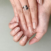 Hands featuring MIBLAB You and Me press-on nails in natural nude beige tone, elegant reusable manicure from Geneva boutique.