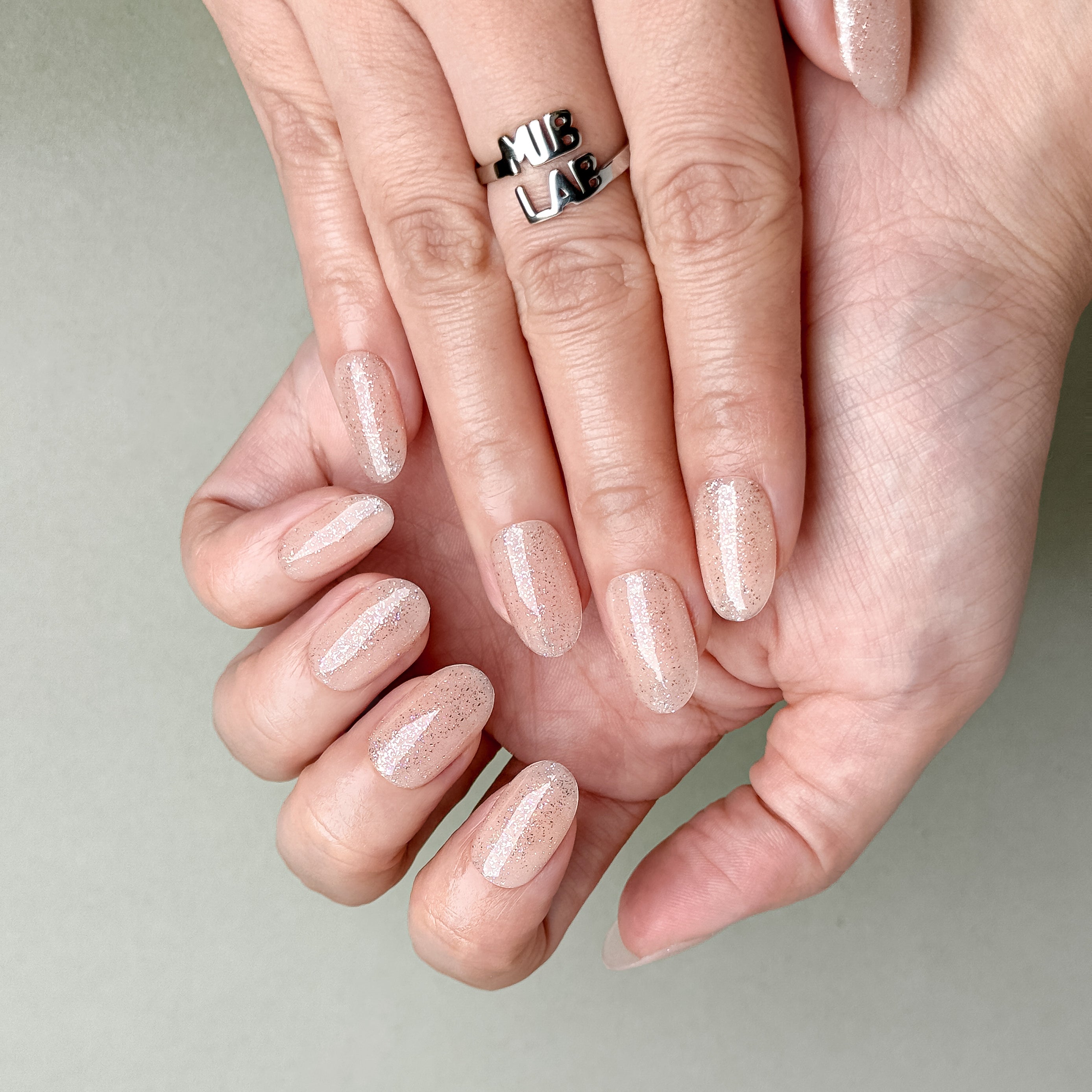 Hands featuring MIBLAB You and Me press-on nails in natural nude beige tone, elegant reusable manicure from Geneva boutique.