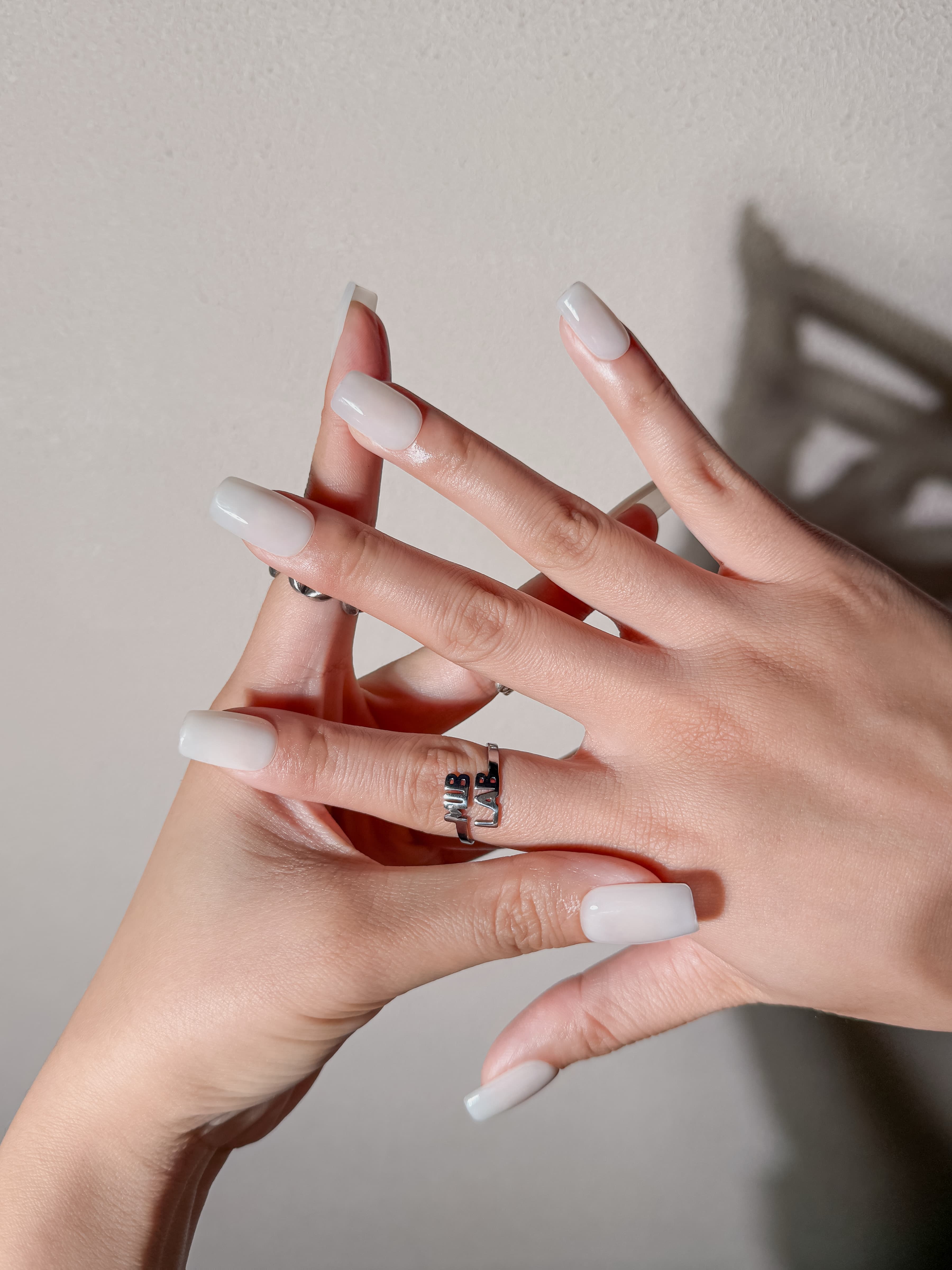 Détail Milk+ sur mains : faux ongles premium réutilisables blanc laqué, style quotidien minimal chic, Suisse.