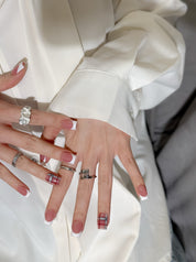 Manucure Frencherry portée : press on nails rose avec french blanche, accent plaid rouge, look élégant, ongles sans gel, Genève.
