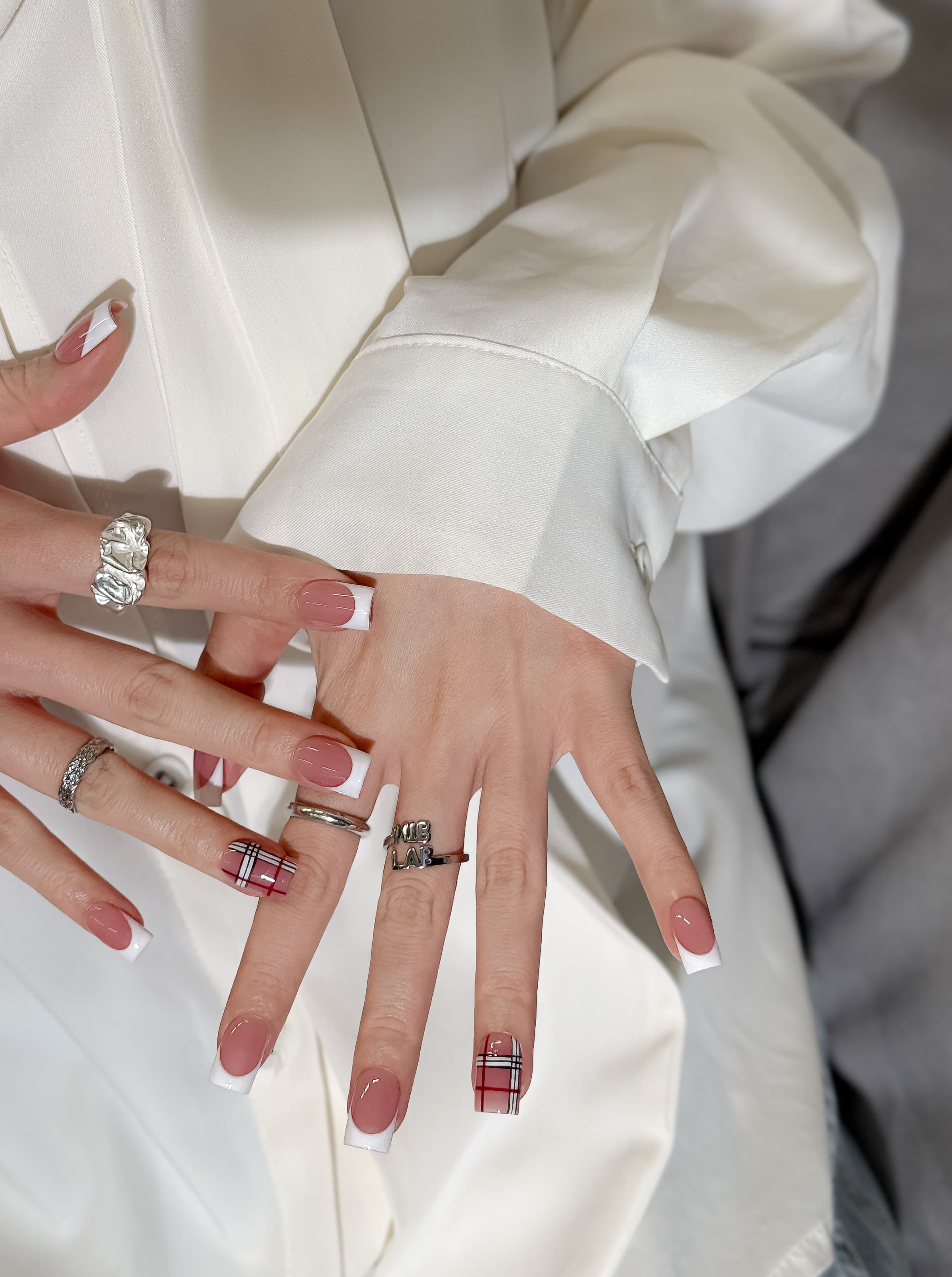 Manucure Frencherry portée : press on nails rose avec french blanche, accent plaid rouge, look élégant, ongles sans gel, Genève.