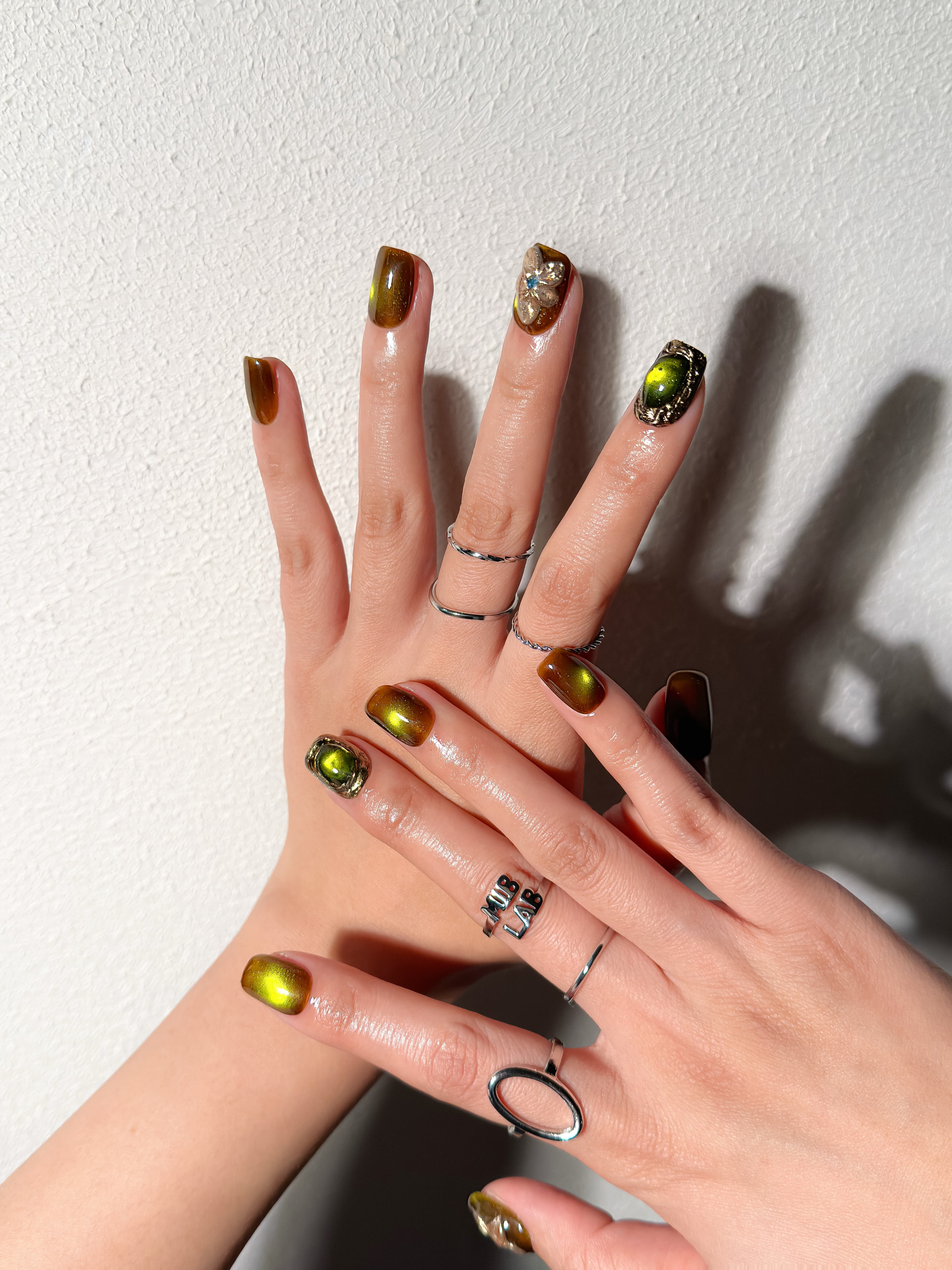 Détail Into the Wild sur mains : faux ongles premium réutilisables vert olive brillant, style événement, tenue longue durée, Suisse.