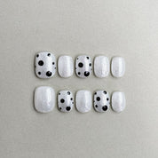Just : faux ongles réutilisables blanc laiteux avec pois noirs, press on nails premium, finition brillante style minimal.