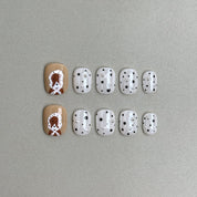 Poppy : faux ongles réutilisables blanc laiteux à pois noirs, accents brun caramel et fleur blanche, press on nails premium.
