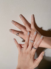 Manucure Le Toi portée : press on nails nude nacré avec fleurs blanches, look doux et élégant, ongles sans gel, Genève.