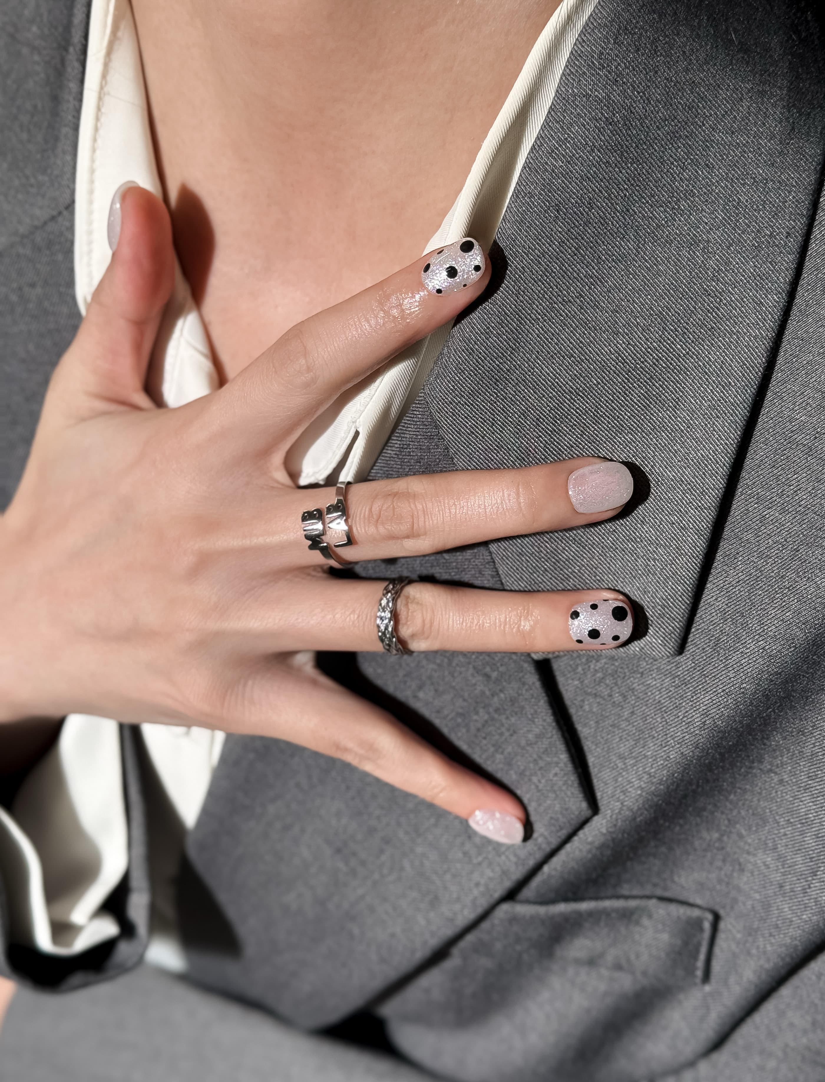 Manucure Just portée : press on nails blanc à pois noirs, look épuré et moderne, ongles sans gel, Genève.