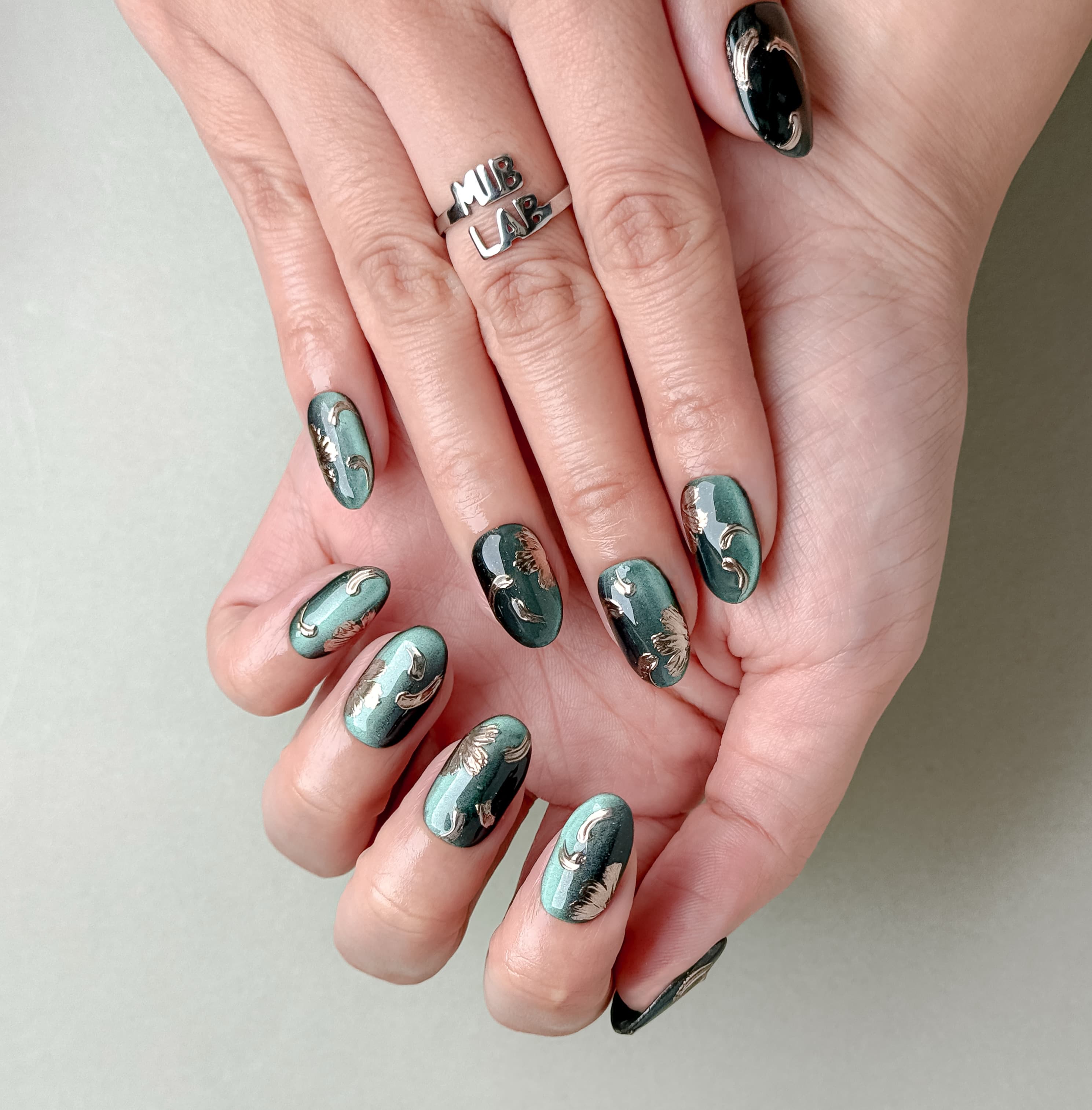 Manucure Jade portée : press on nails vert jade, détails bronze, look chic et moderne, ongles sans gel, Genève.