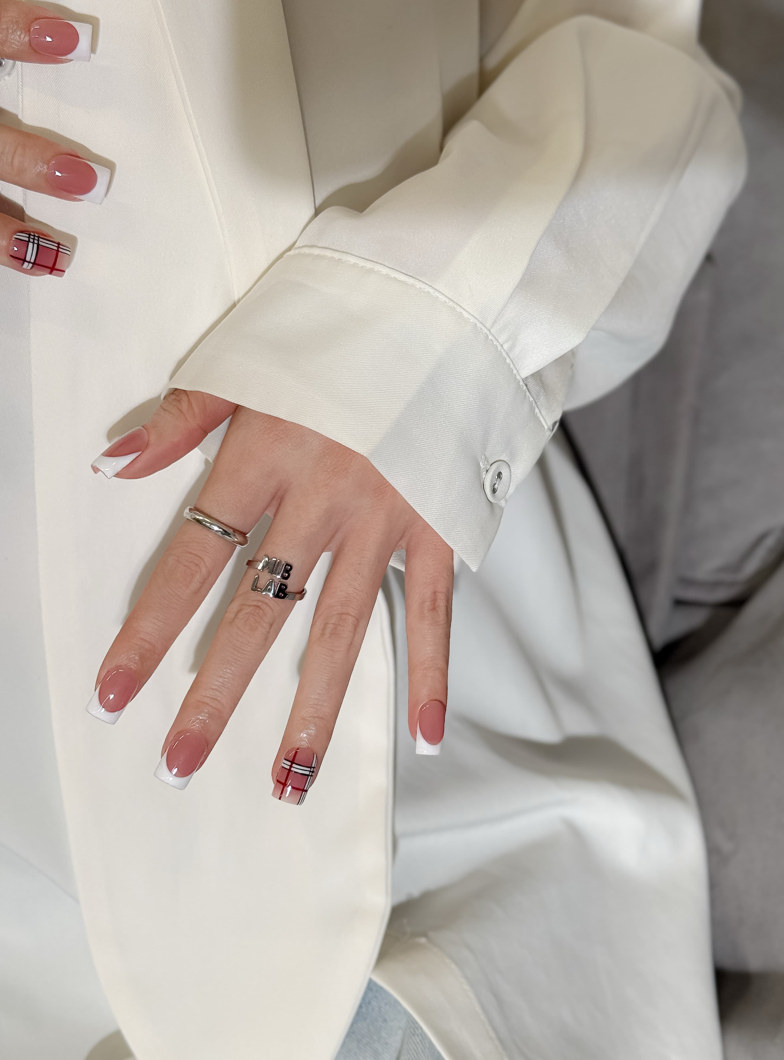 Détail Frencherry sur mains : faux ongles premium réutilisables style french et tartan, tenue longue durée, Suisse.